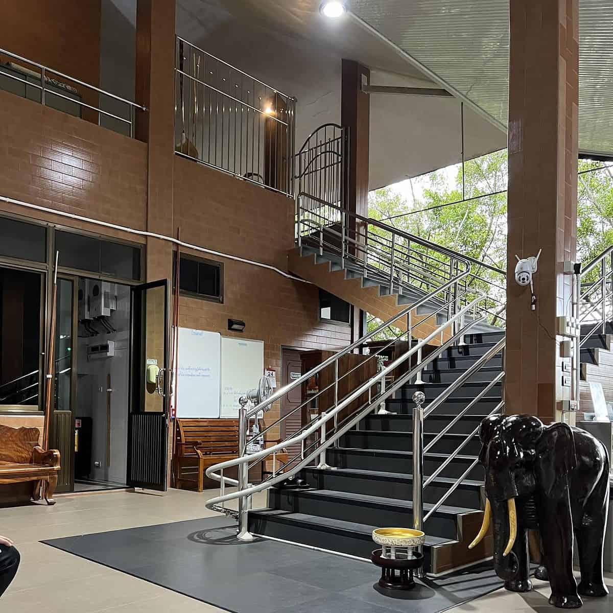 Indoor stairwell, with an assisted stairlift railing. Large Wooden elephant sculpture to the right of the stair